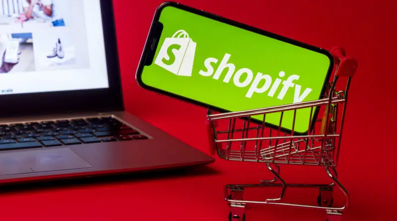 cell phone in shopping cart next to computer
